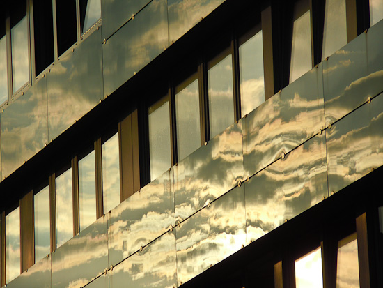 Sonne und Wolken spiegeln sich in einer Fassade